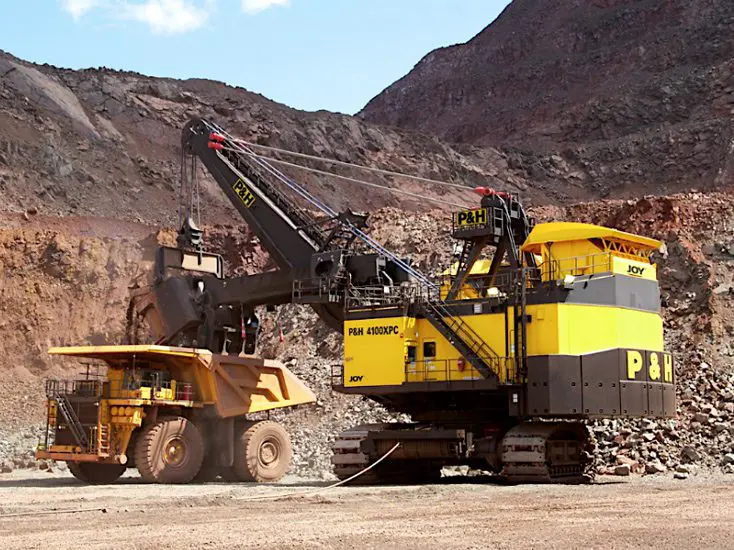 A large yellow and black truck is parked in the dirt.